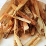 Beef tallow fries in a brown paper cone spilling onto a counter