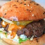A burger with cheese and pickles on a sourdough burger bun.