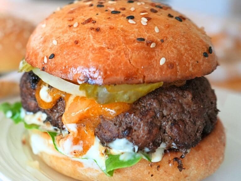A burger with cheese and pickles on a sourdough burger bun.