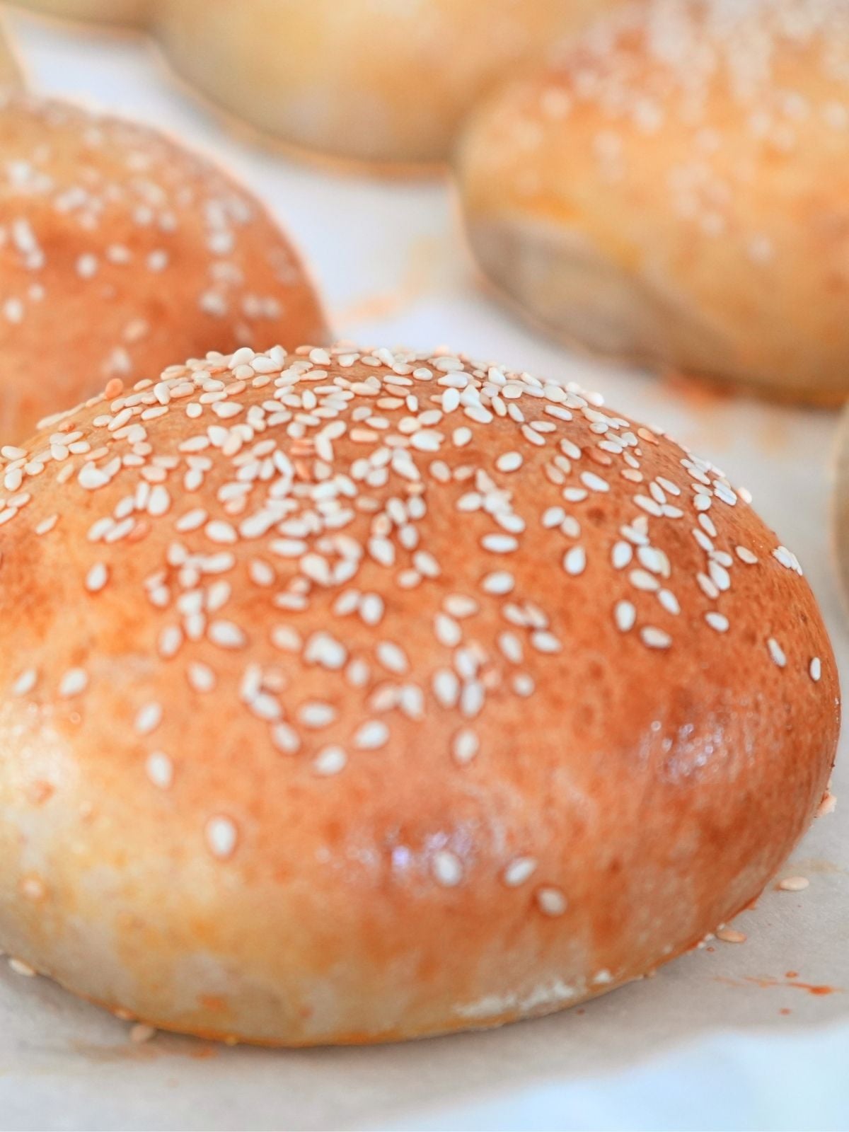Sourdough burger buns on a baking sheet.