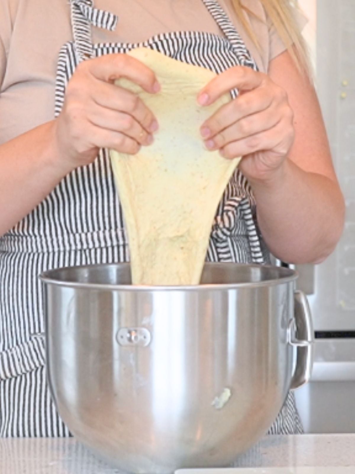 Woman performing the windowpane test on dough.