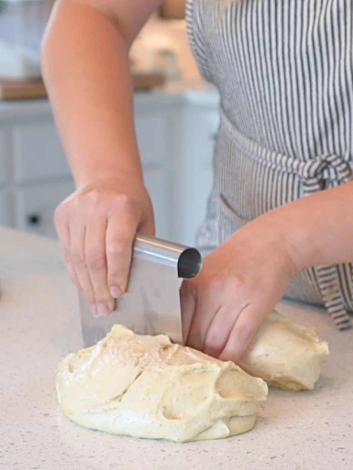 Woman cutting dough with bench scraper.