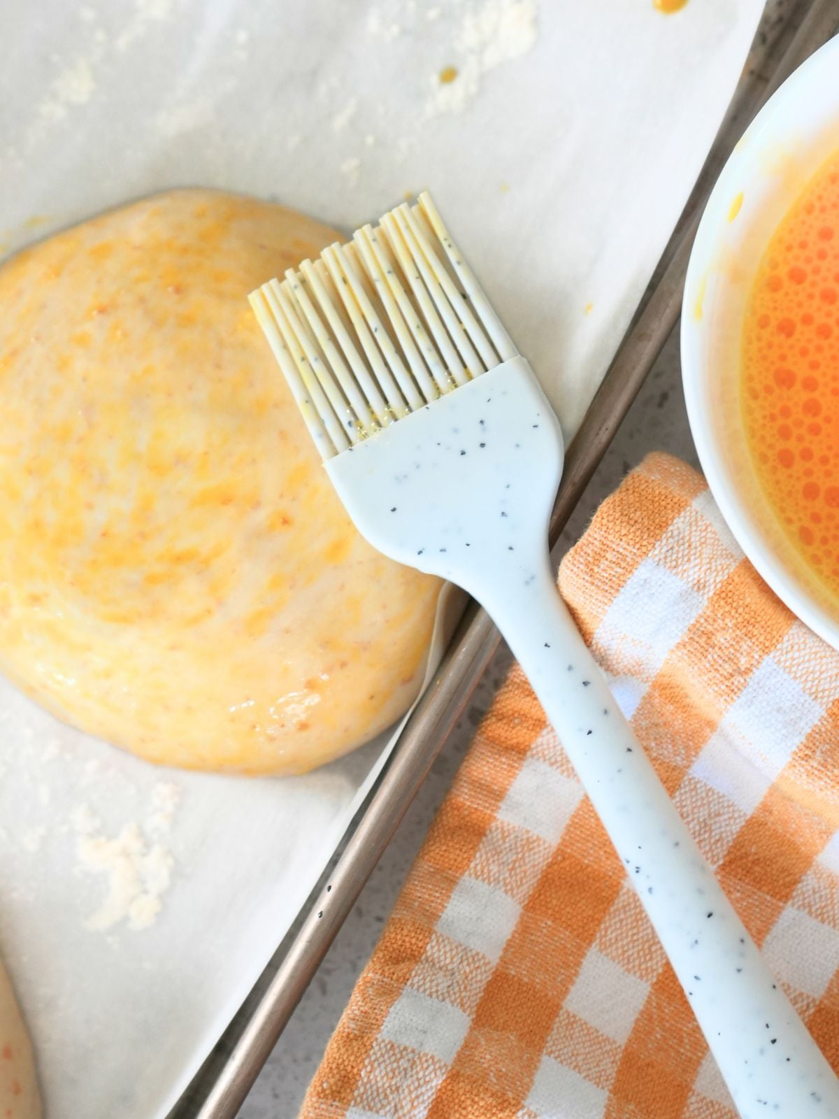 Sourdough burger buns dough with egg wash and silicone brush.
