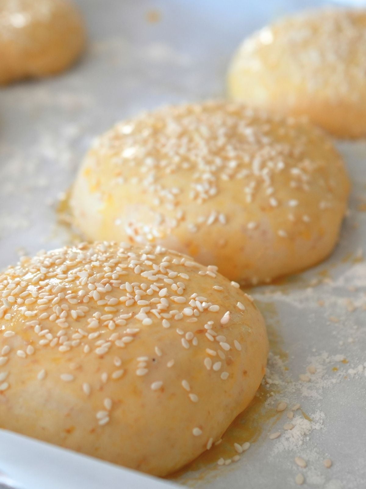 Sesame seeds on unbaked sourdough burger buns.