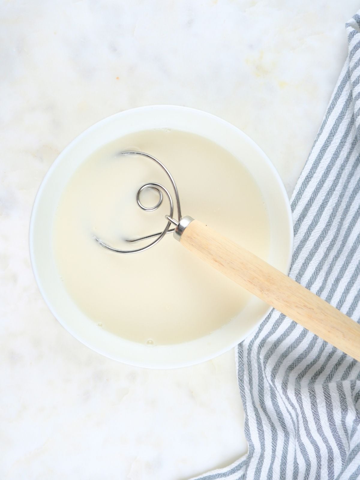 Water and sourdough starter mixed together in a white bowl.