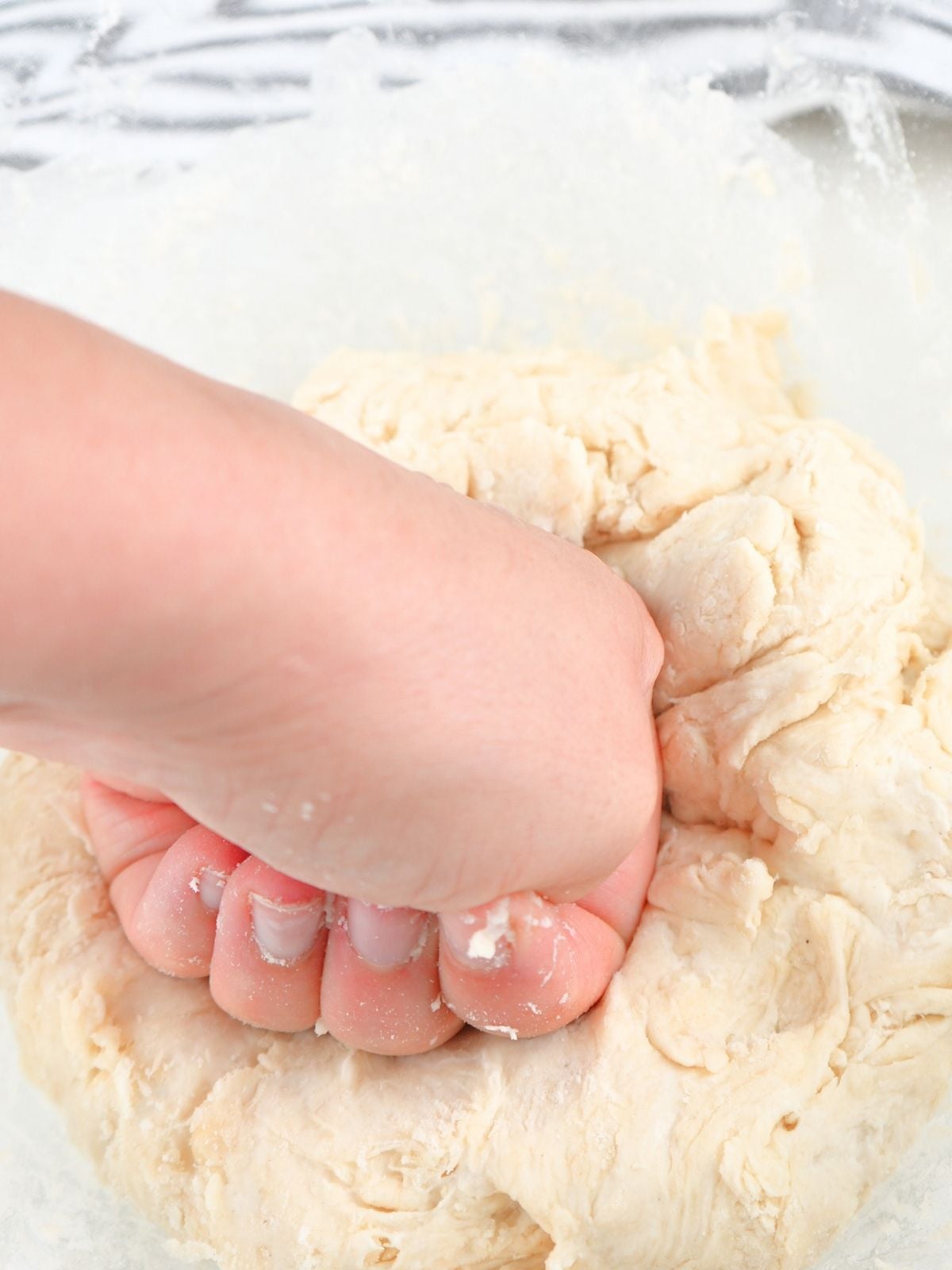 A hand kneading sourdough discard tortilla dough.