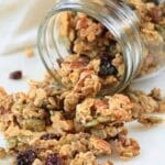 Sweet and salty sourdough granola spilling out of a glass mason jar onto a counter