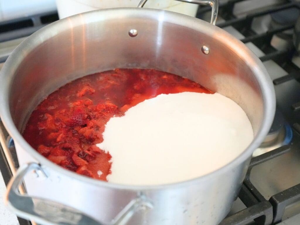 Strawberries, sugar, and lemon juice in a stainless steel stock pot.