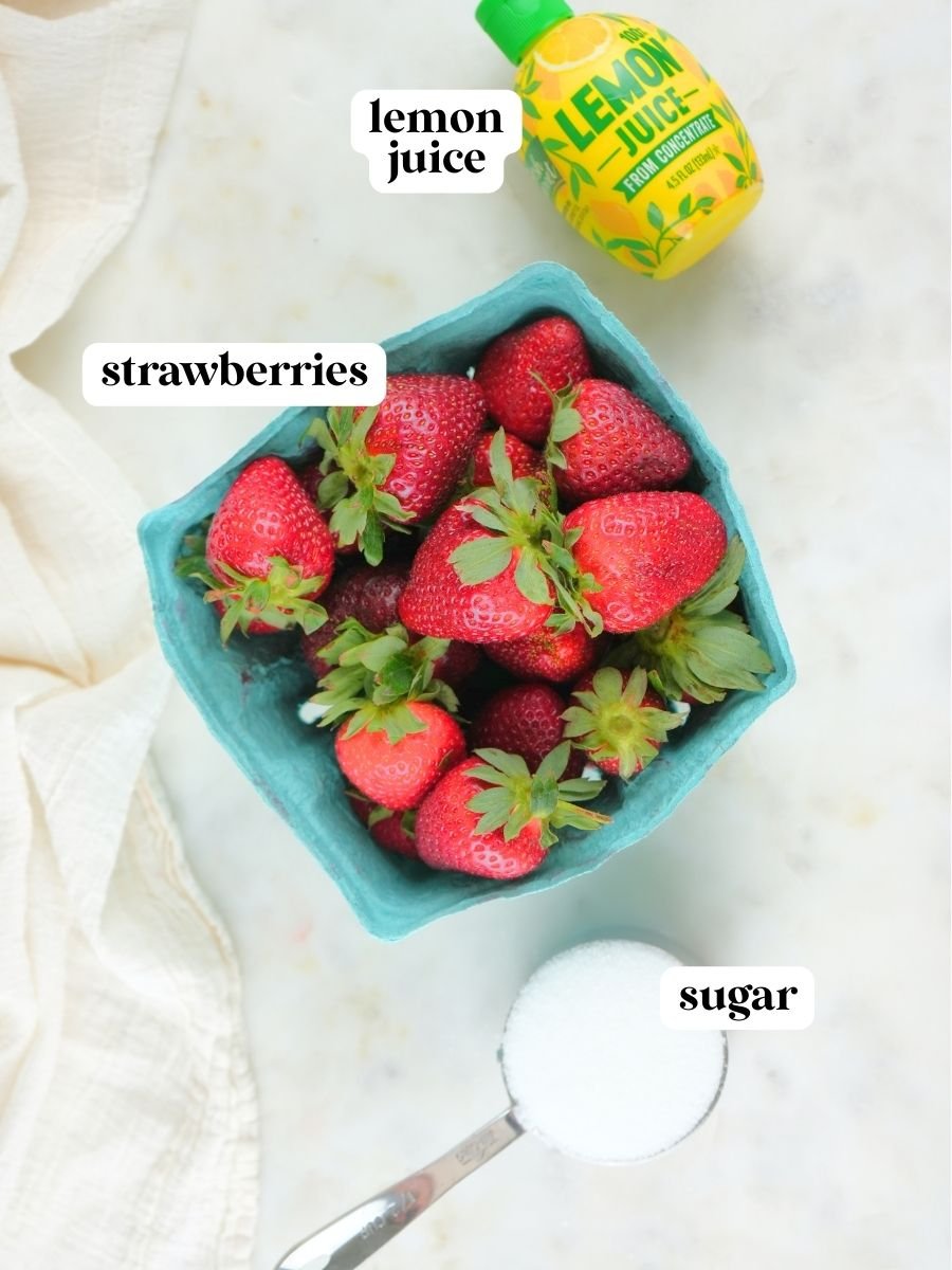 Canned strawberry jam recipe ingredients on display: strawberries, lemon juice, and sugar