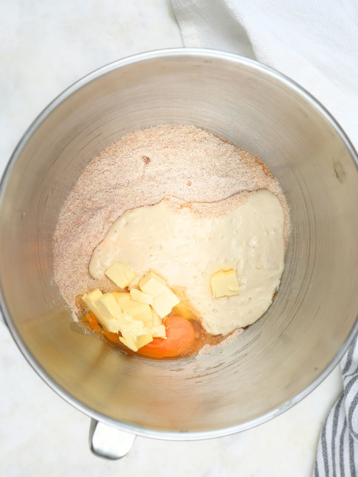 A stand mixer bowl filled with the ingredients for fresh-milled sourdough sandwich bread.