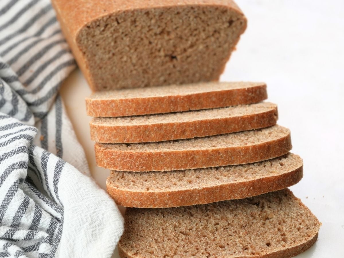 Slices of fresh-milled sourdough sandwich bread with a loaf in the background.