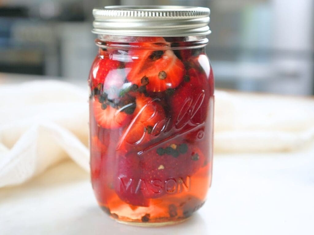 Pickled strawberries in a mason jar sealed with a lid.