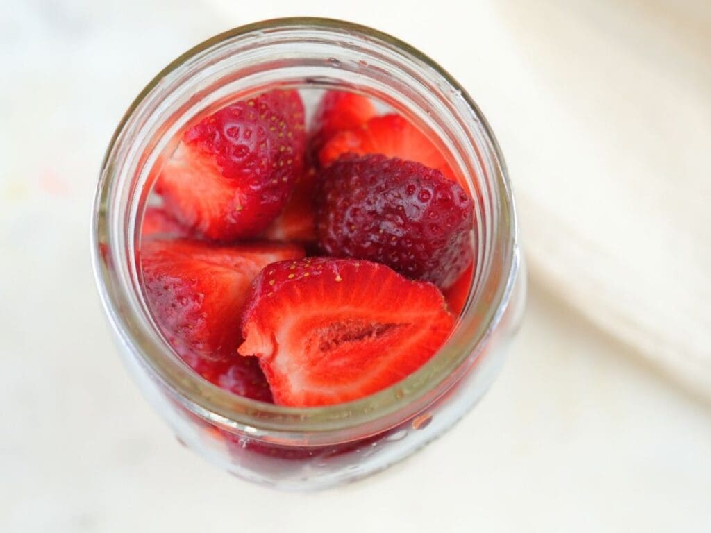 Halved strawberries in a mason jar.