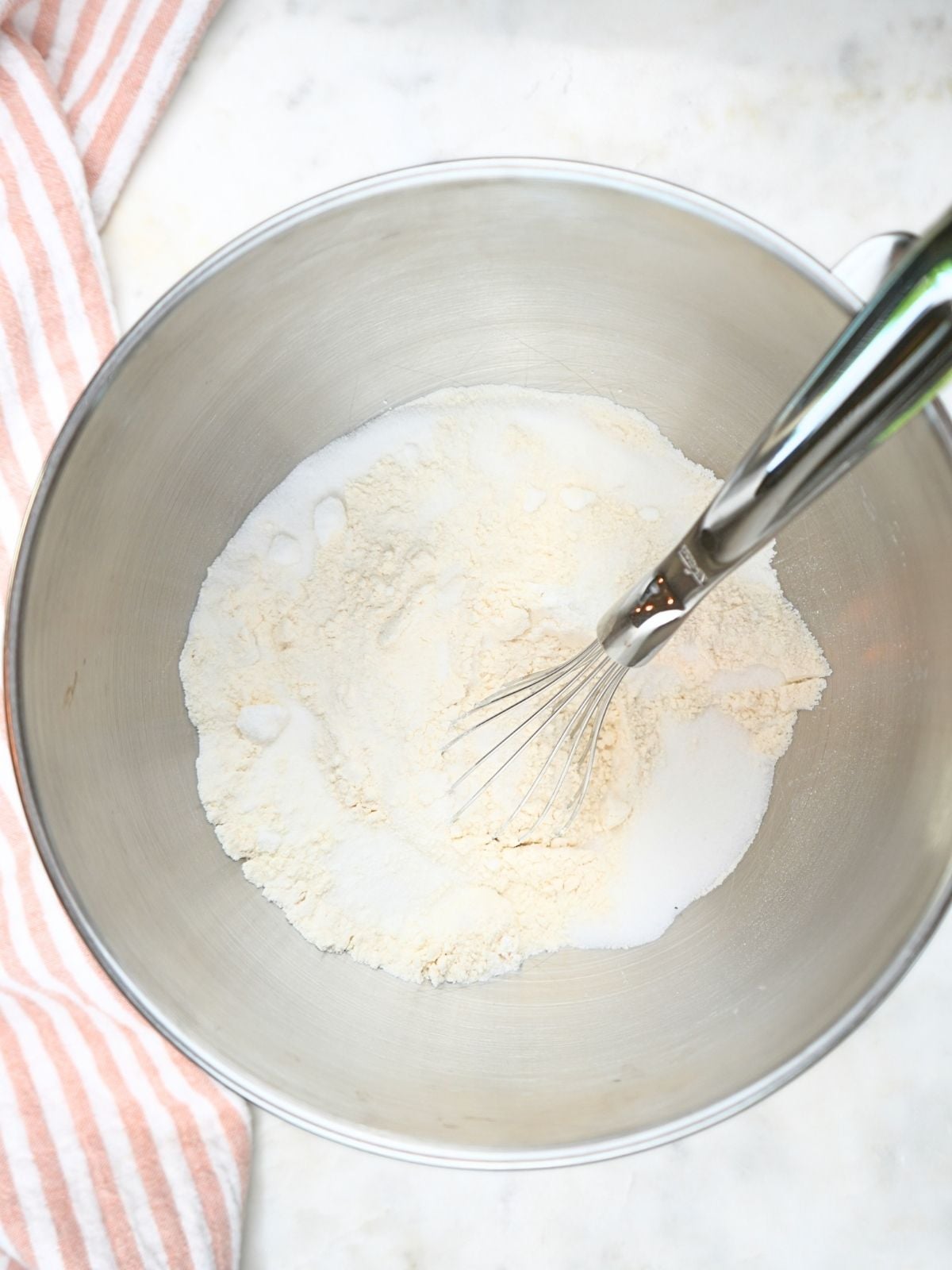 A mixing bowl with dry ingredients and a whisk.