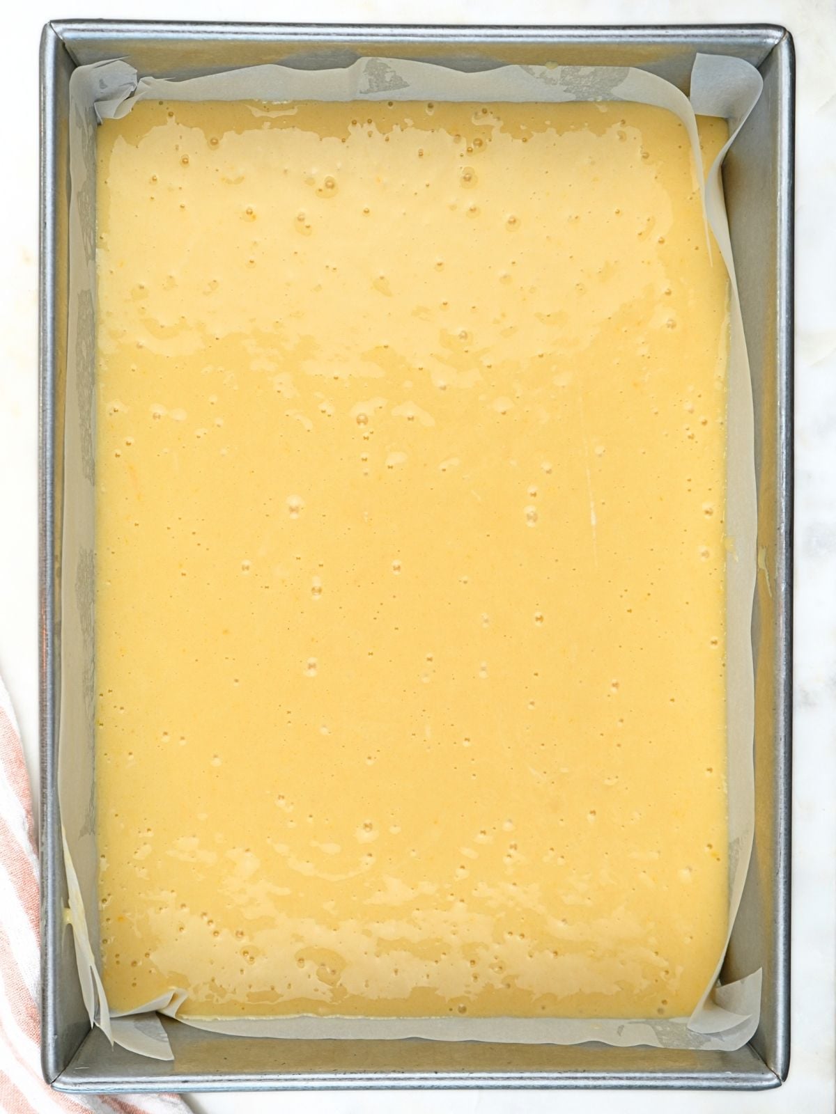 Cake batter in a parchment-lined 9x13 cake pan.
