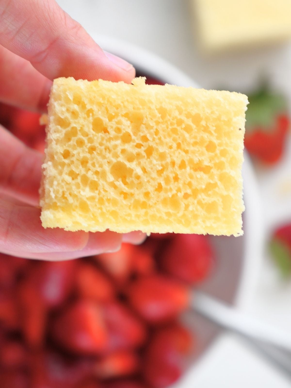 A hand holding a square of sourdough shortcake.