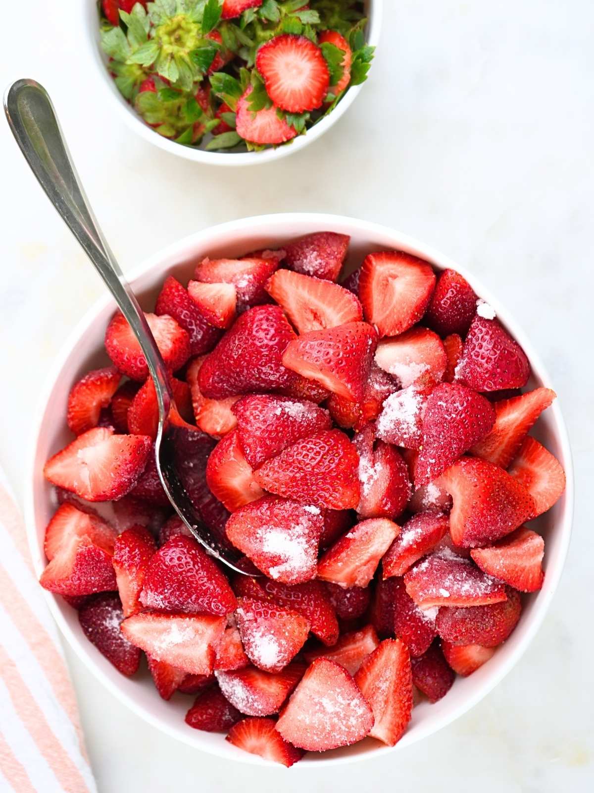 A bowl of fresh berries with sugar on top and a spoon.