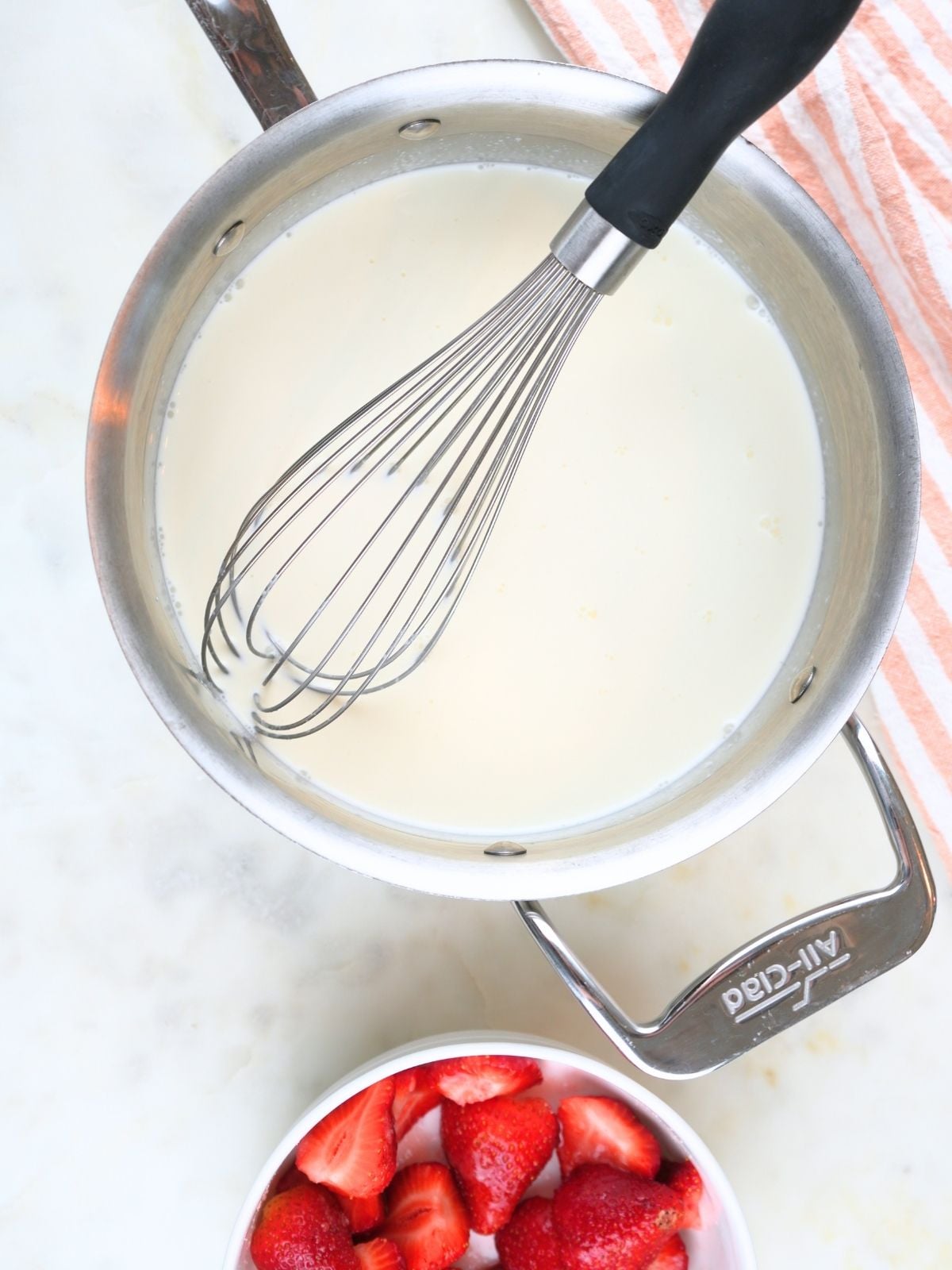 Milk, cream and sugar is a stainless steel pot with a whisk.