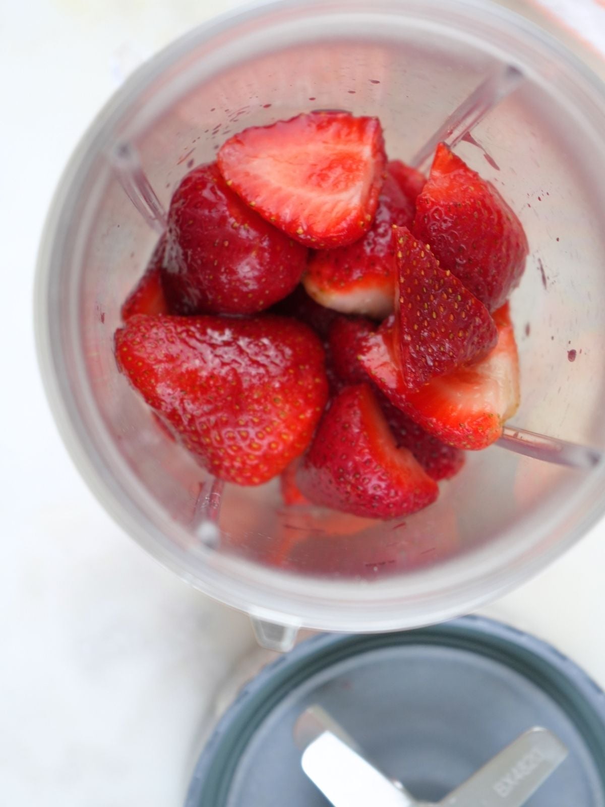 Strawberries in a blender container, shown next to the blade.