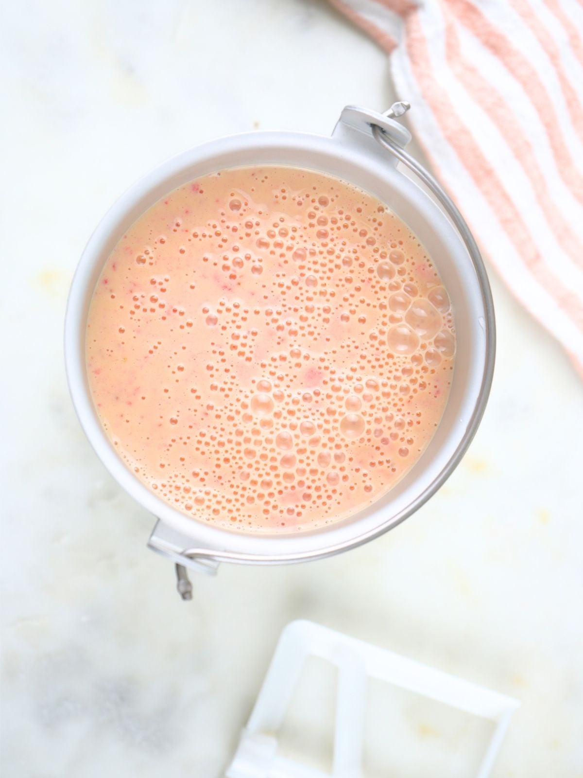 Strawberry ice cream mixture in a ice cream maker container