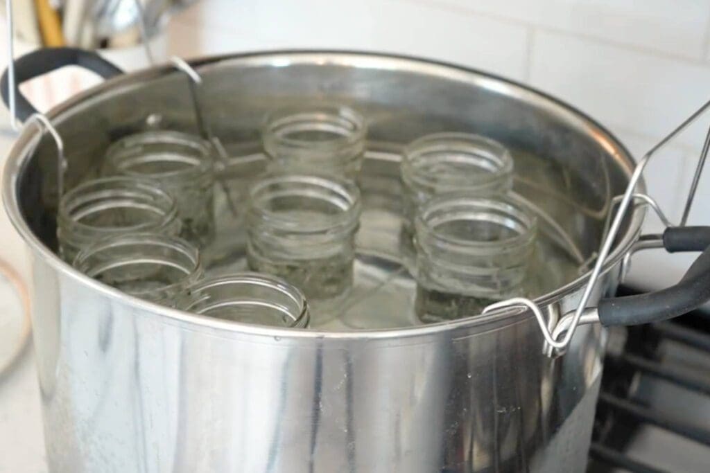 A filled water bath canner with nine half-pint jars in it