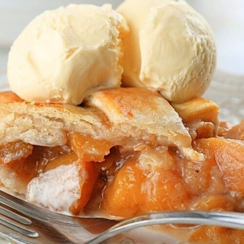 A slice of sourdough peach pie topped with two scoops of vanilla ice cream