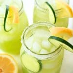 Three jars of cucumber lemonade garnished with sliced lemon and cucumber