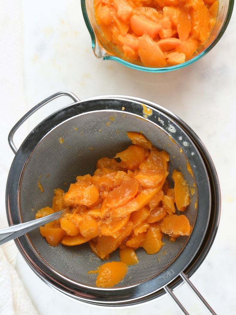 Canned peaches straining in a bowl