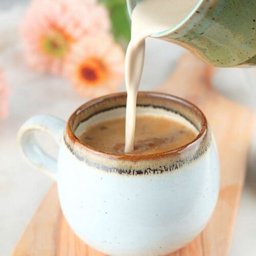 Homemade brown sugar coffee cream being poured into a coffee mug.