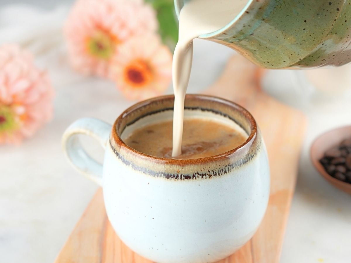 Homemade brown sugar coffee cream being poured into a coffee mug.