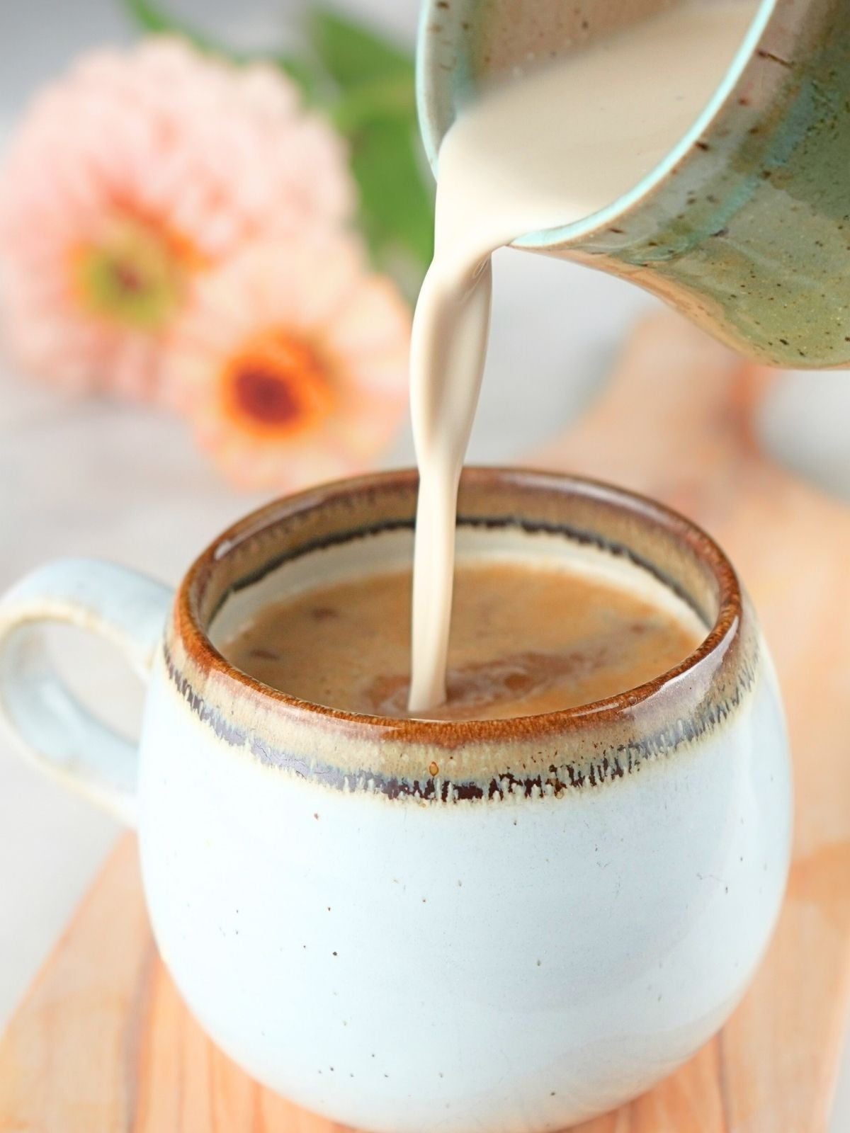 Brown sugar coffee cream being poured into a cup of coffee .