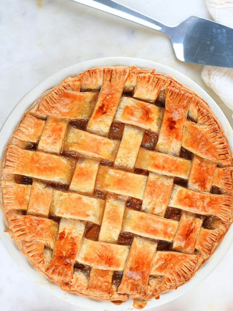 Baked sourdough peach pie with a lattice crust, shown next to a pie server