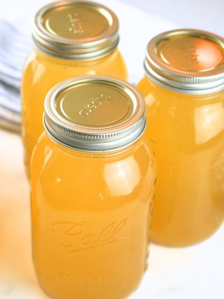 Home-canned chicken broth on a counter, sealed with lids and rings.