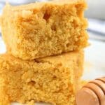 Two slices of cornbread made with fresh milled flour next to a honey dipper