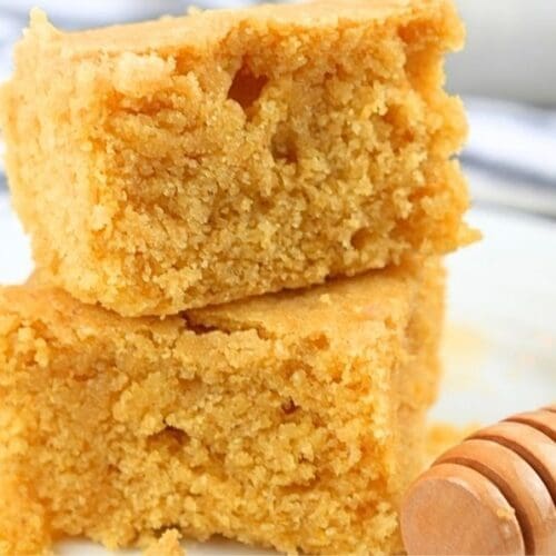 Two slices of cornbread made with fresh milled flour next to a honey dipper