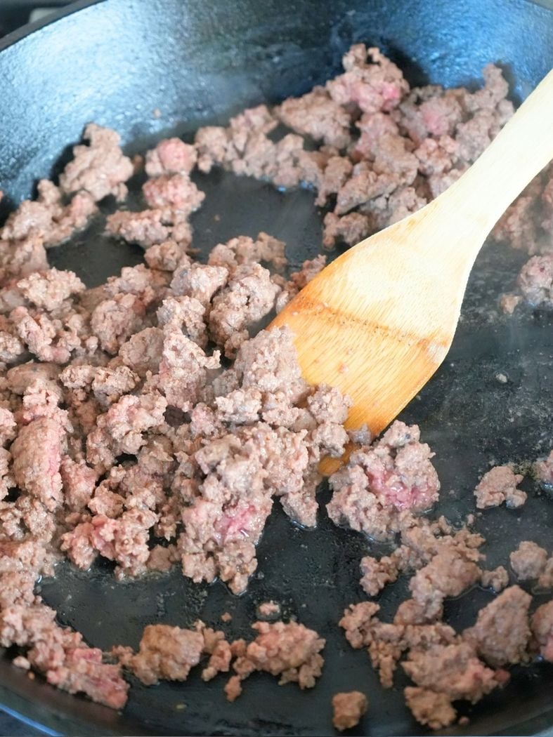 Ground beef browning in a cast iron skillet