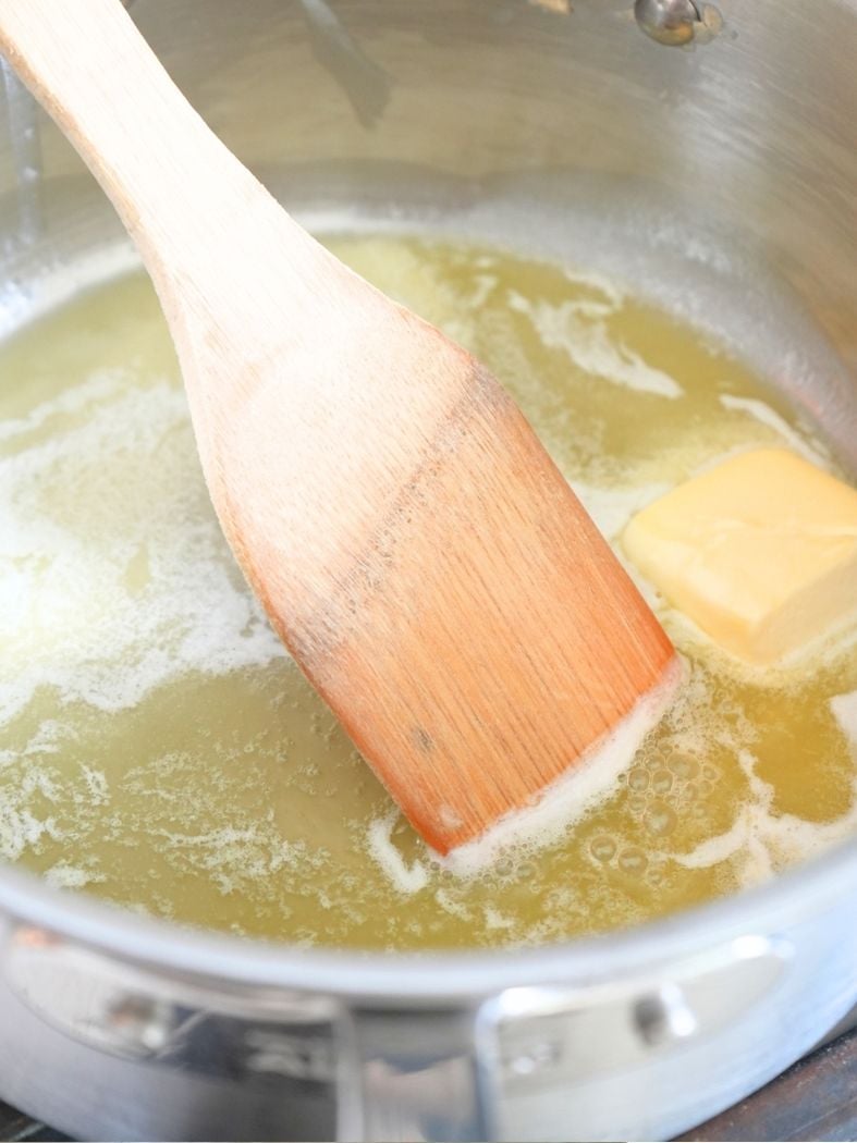 Butter melting in a sauce pan, shown with a wood spoon