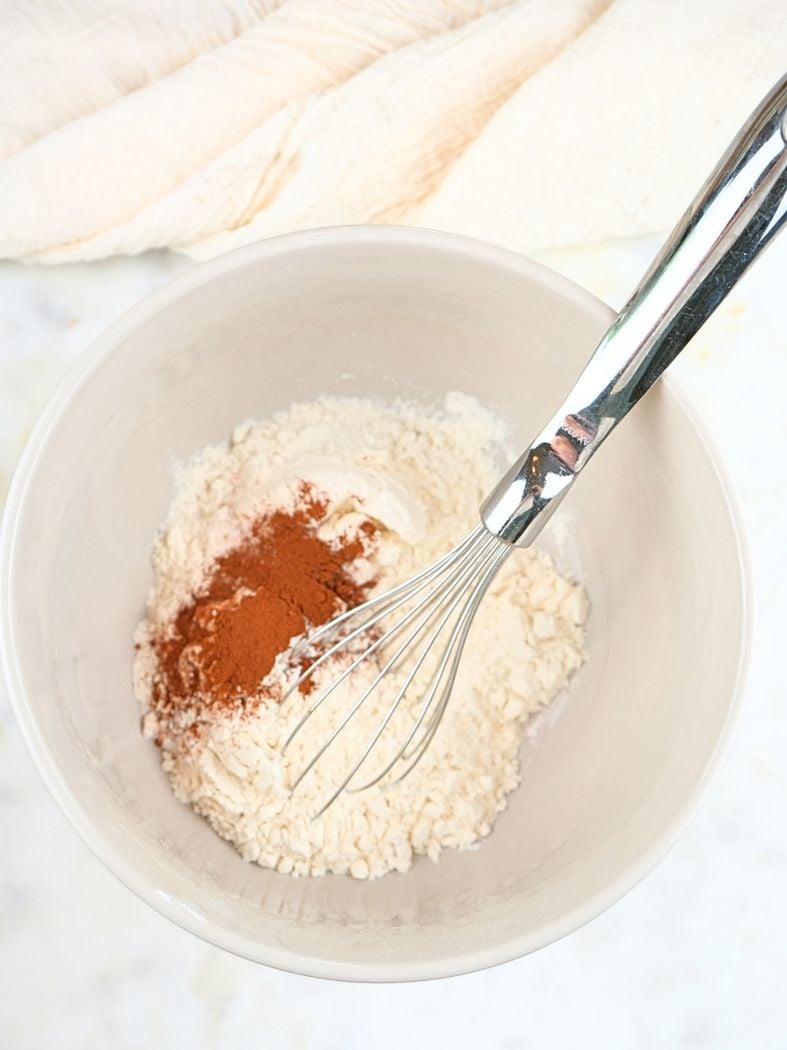 Sourdough zucchini bread dry ingredients in a mixing bowl, shown with a whisk