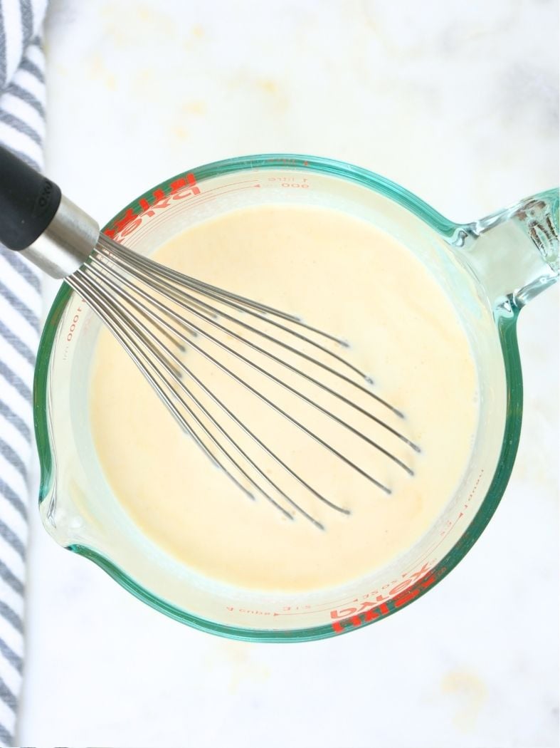 A large glass measuring cup filled with homemade vanilla ice cream ingredients