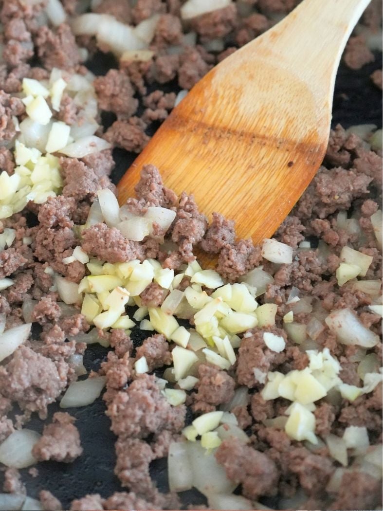 Garlic added to a skillet with browned ground beef