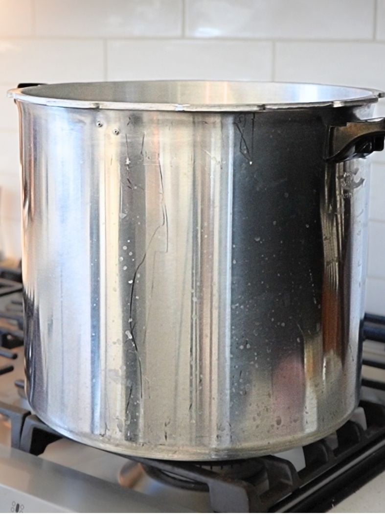 A pressure canner preheating on a gas stove