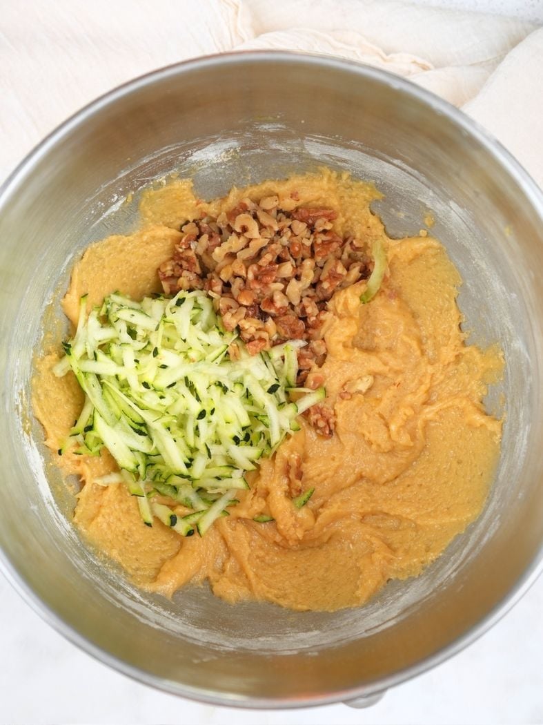 Sourdough discard zucchini bread batter with shredded zucchini and walnuts on top