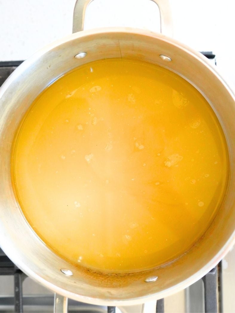 Chicken broth coming to a boil on a stove