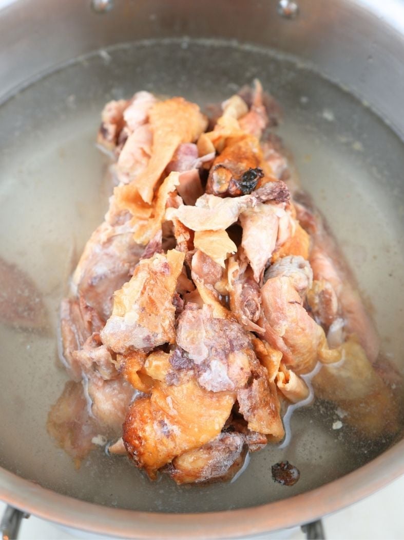 Chicken bones in a water in a stainless steel pot.