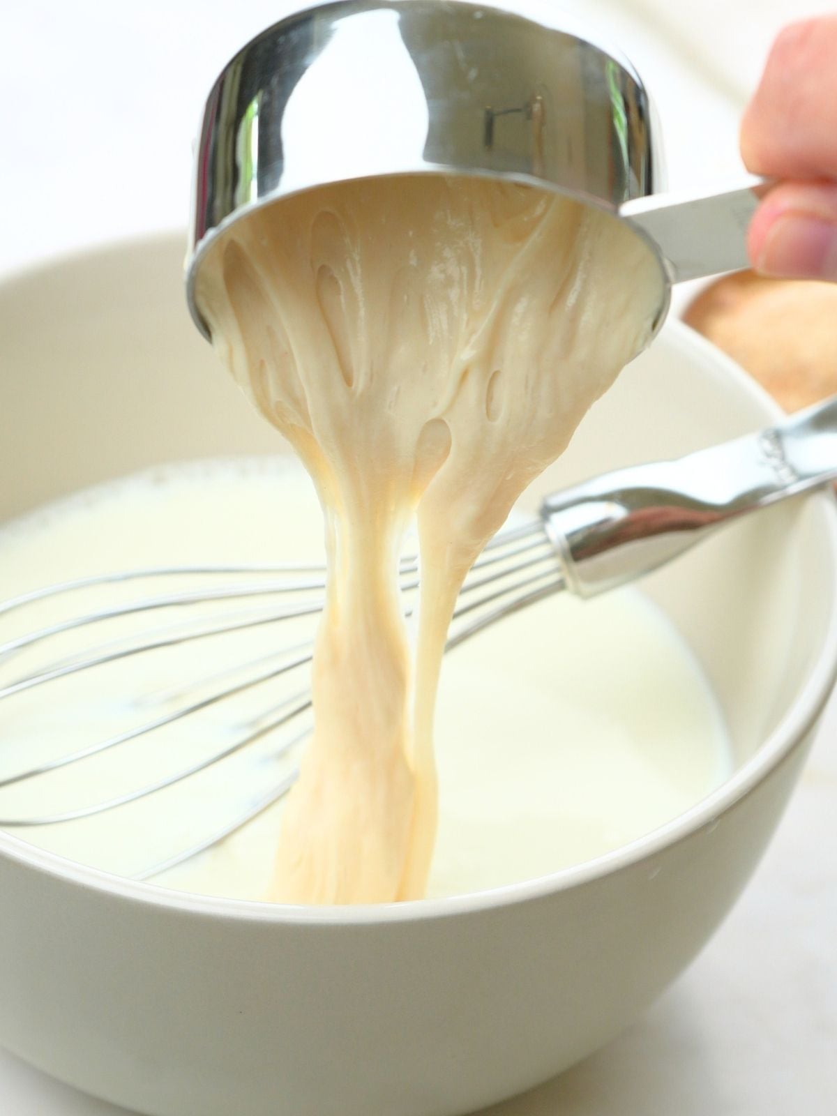 Sourdough starter being poured into a bowl of milk.
