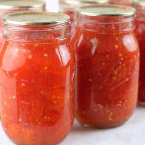 Jars of crushed tomatoes lined up on a counter