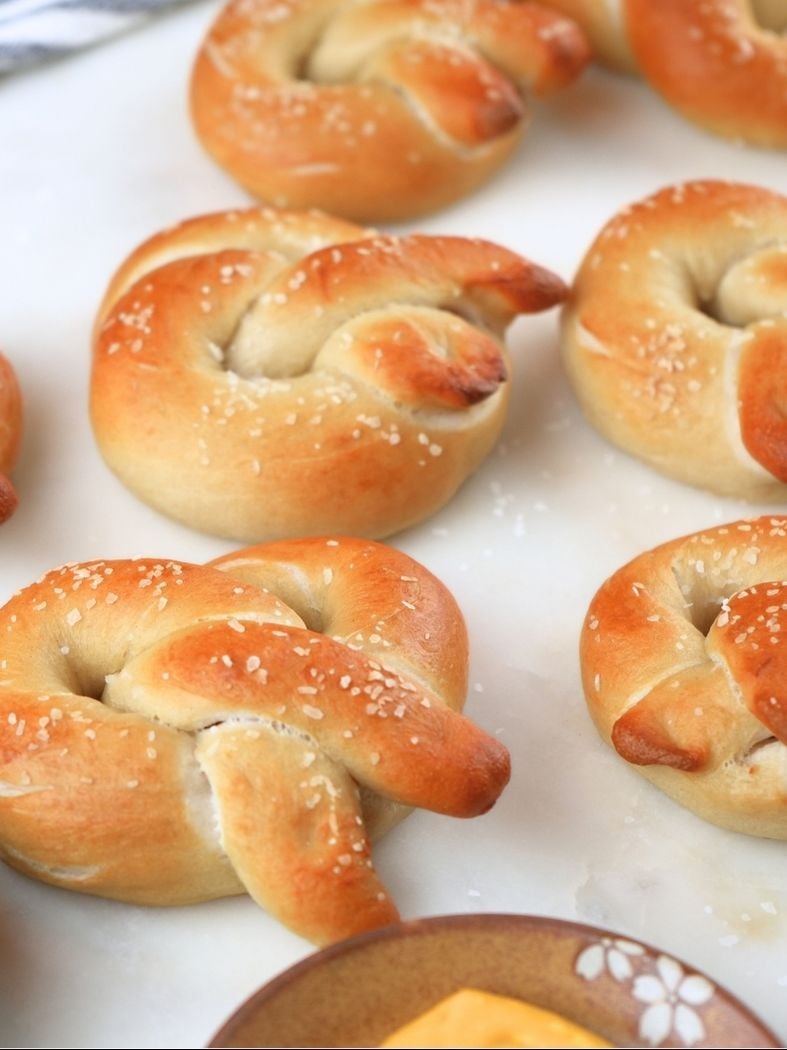 Sourdough soft pretzels resting on a counter top with a dish of mustard in the foreground