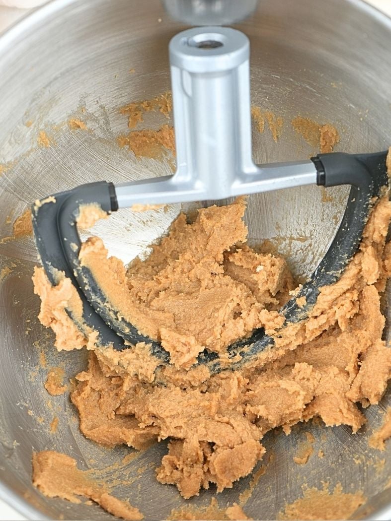 Butter and sugar creamed in a mixing bowl, shown with a paddle attachment