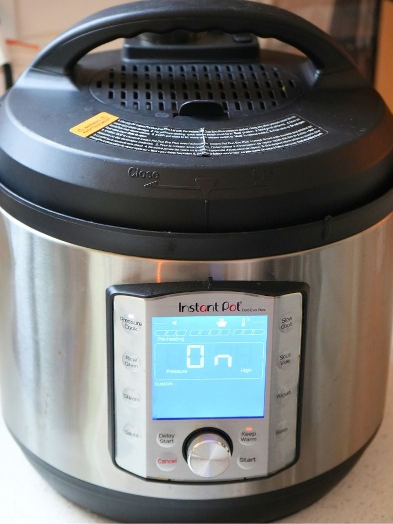 An Instant Pot on a counter with screen lit up