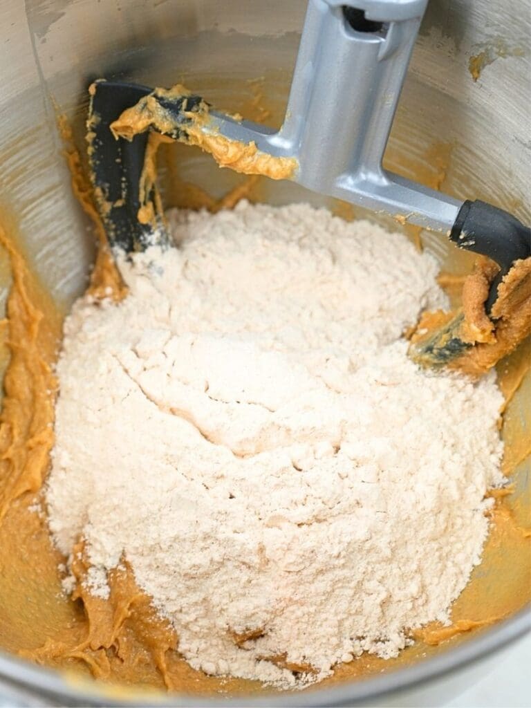 Flour poured over the wet ingredients in a mixing bowl